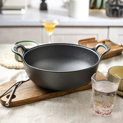 faitout- en- fonte - cocotte- ronde- avec couvercle :  faitout- à- côté- d'un- verre- d'eau
