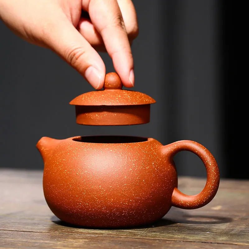 théière artisanale en argile faite main : son couvercle en main